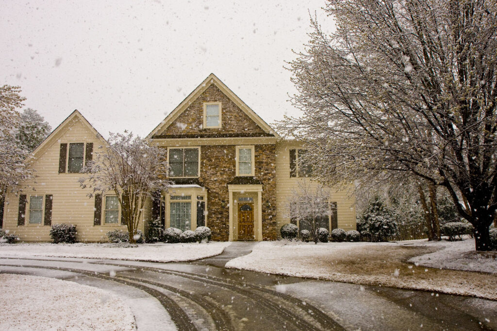 house with trees in snow storm